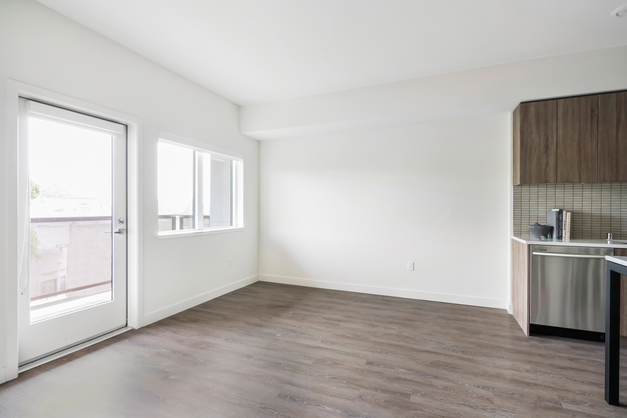 An open plan apartment living room with hardwood floors and a balcony door at the Webster Eleven apartments in downtown Oakland
