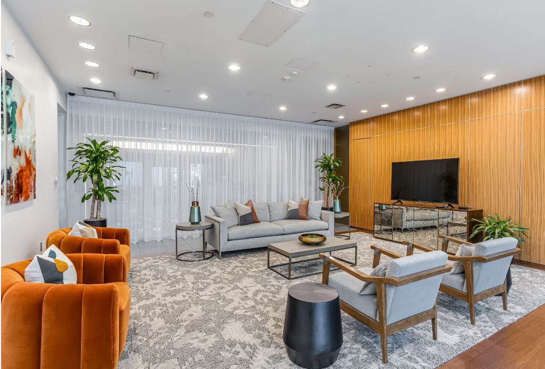 Resident lounge with sofa and 2 chairs, coffee table, and flat screen tv on the wall in the back.