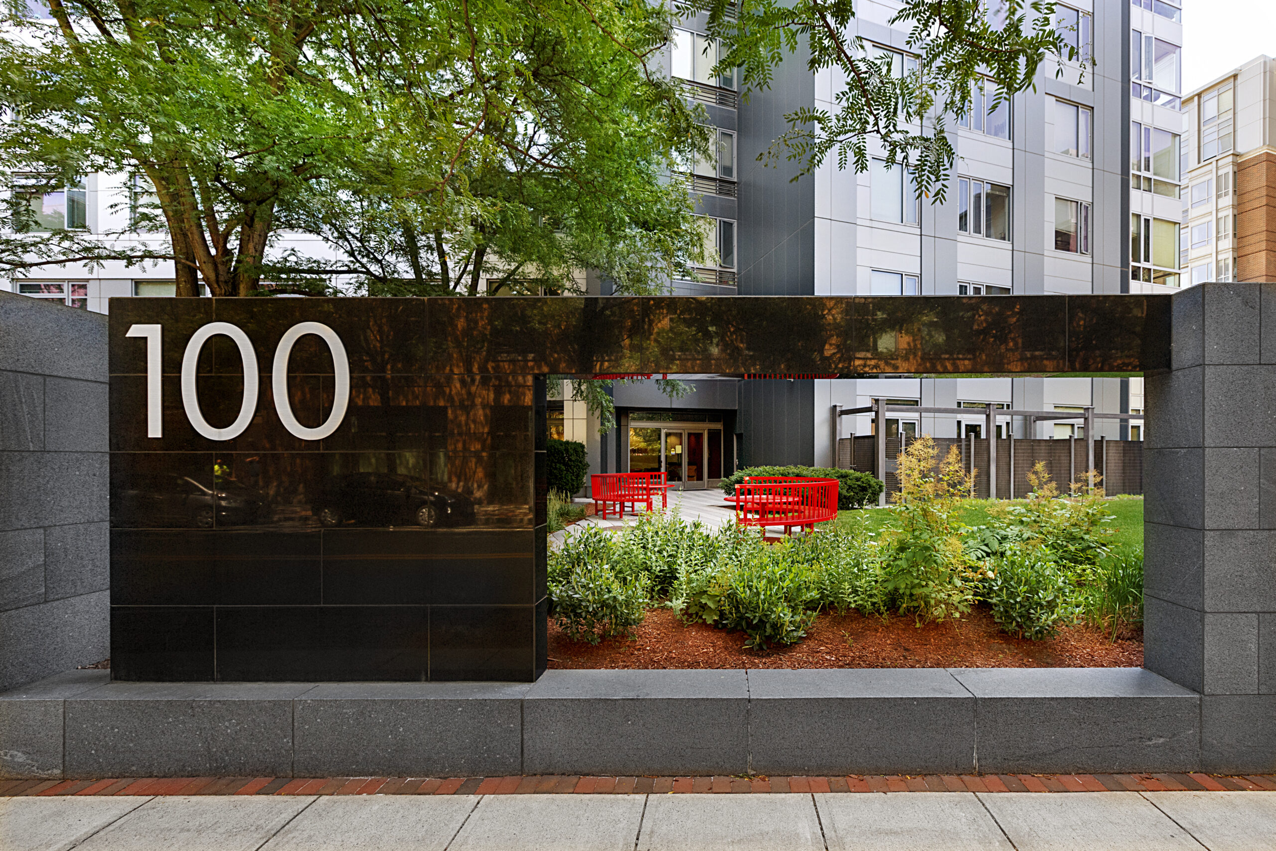 Sign with 100 on it and a cut out with a view of the front entrance into 100 Landsdowne apartment building.