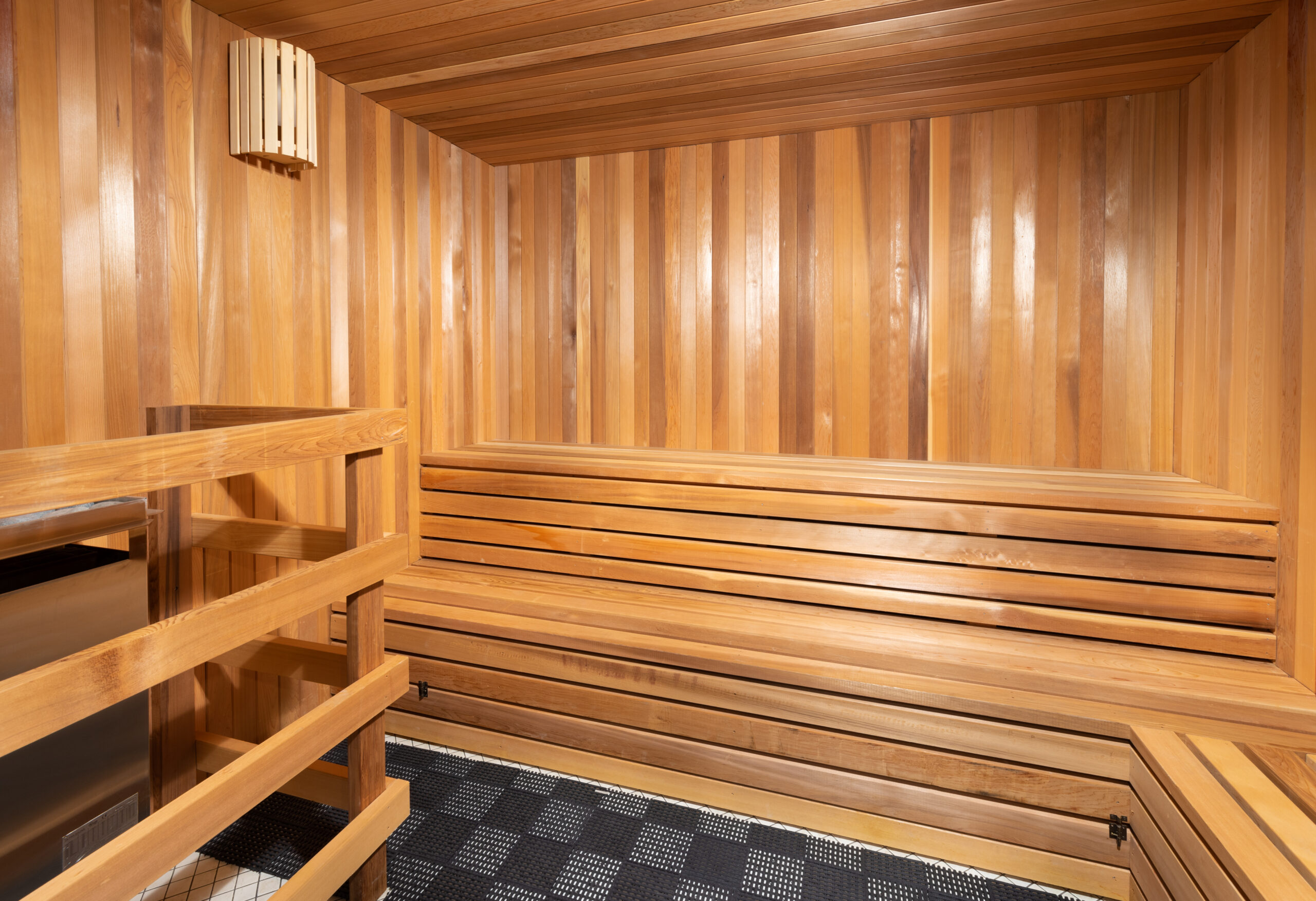 Wood-paneled sauna with bench seating and a modern heating system.