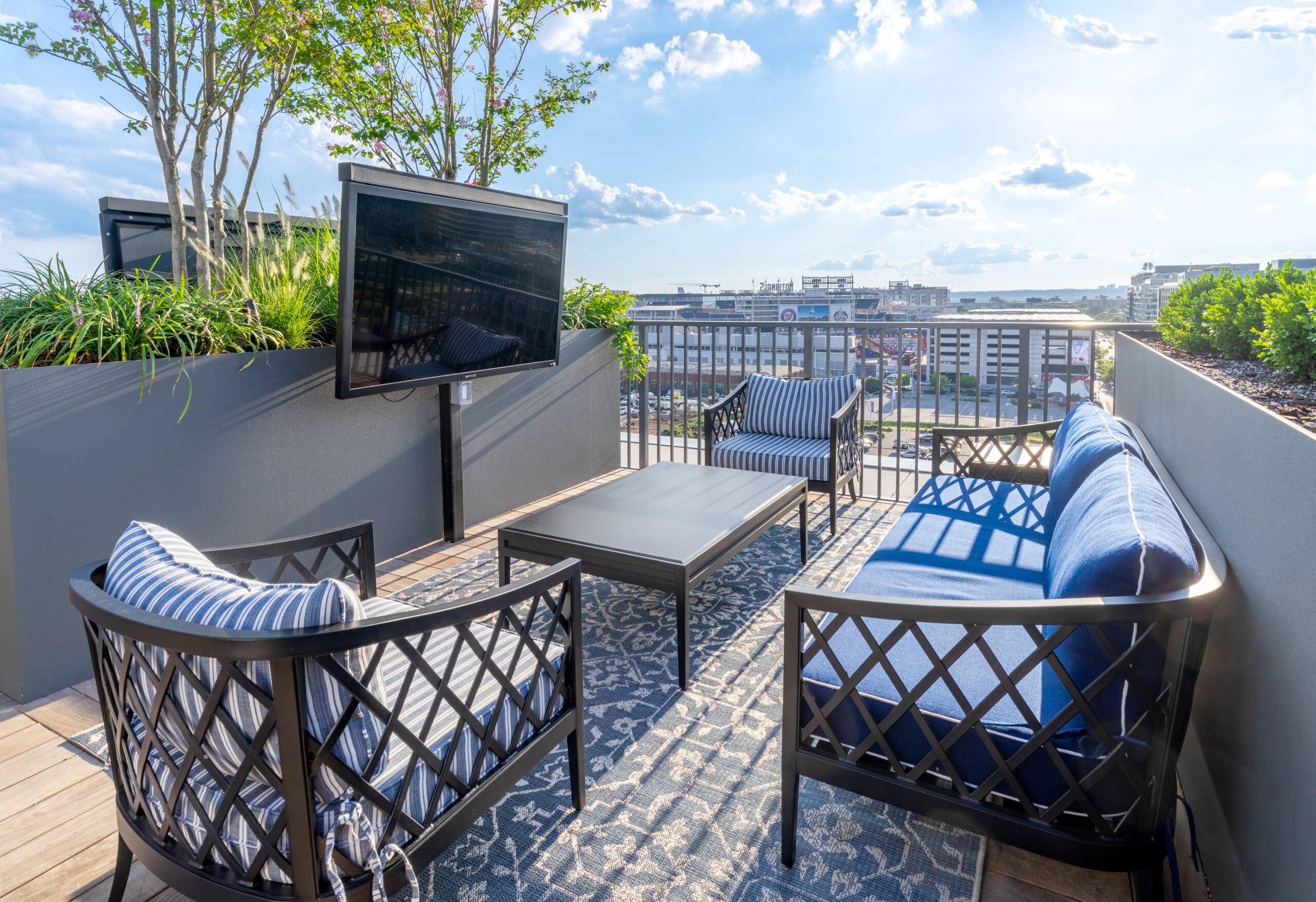 Rooftop lounge area with outdoor seating, a TV, and views of the city skyline.