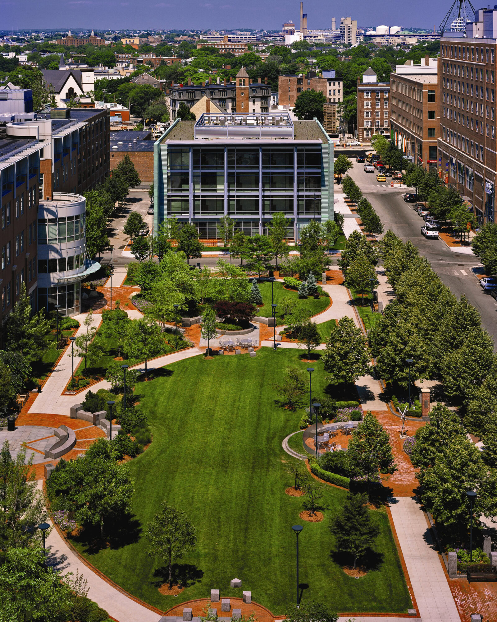 Landscaped lawn area with apartment building with a wall of windows looking onto the lawn.