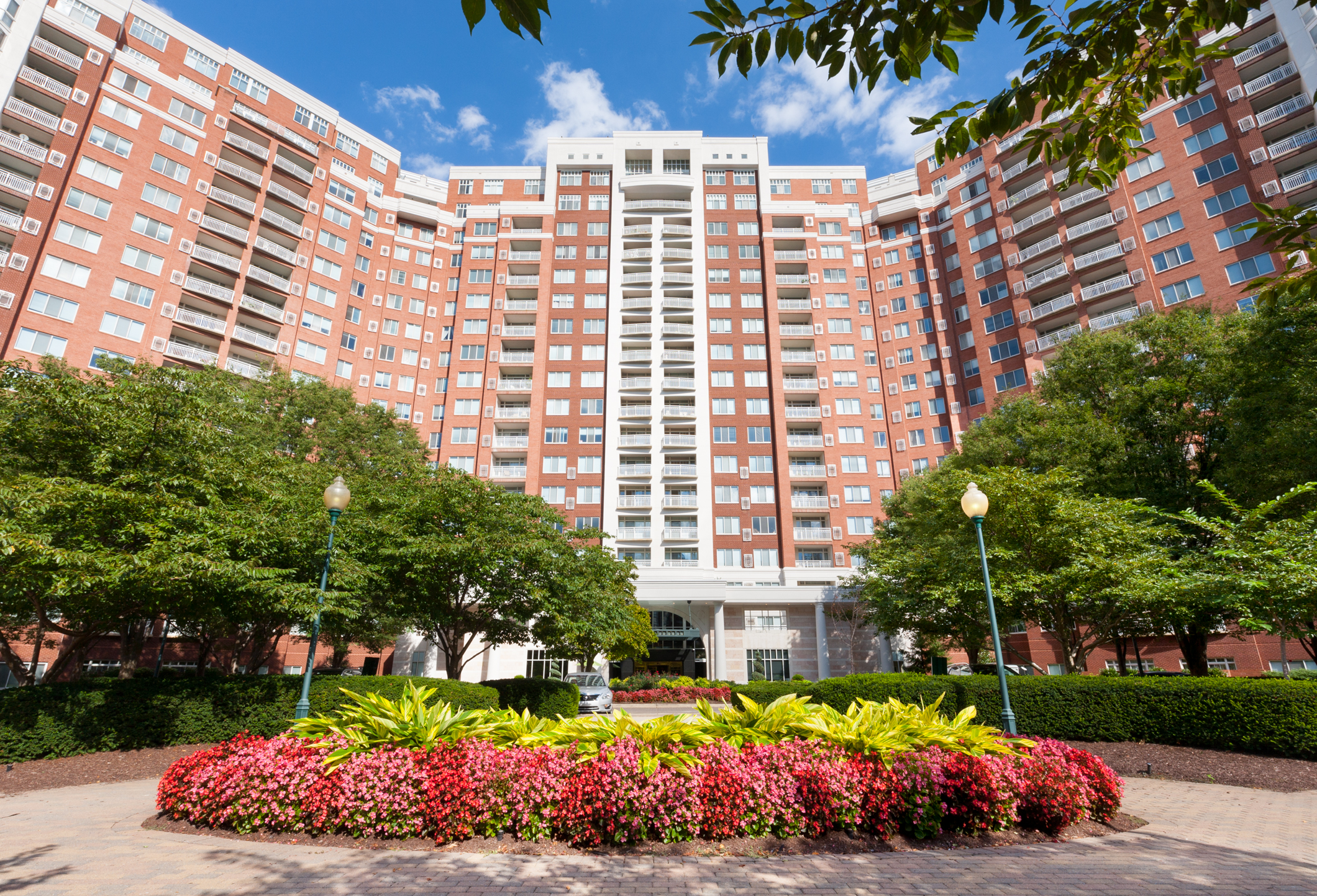 Front entrance of The Grand, a red brick building with beautiful landscaping.