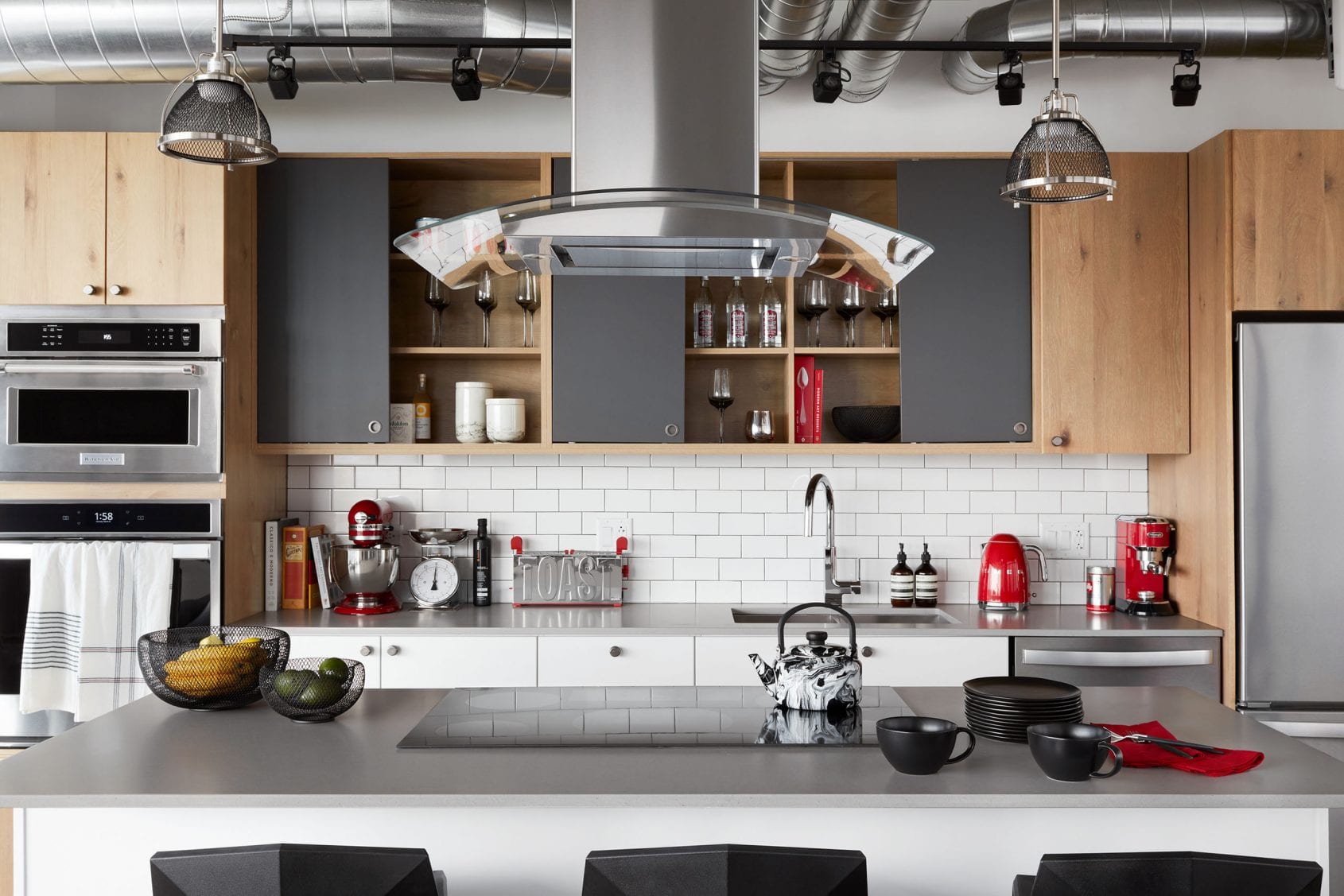 Modern kitchen with stainless steel appliances, open shelving, and industrial finishes.