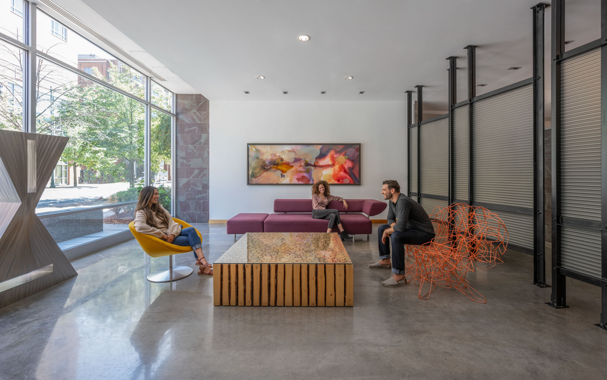 Three friends chat around a stylish coffee table in a common area.