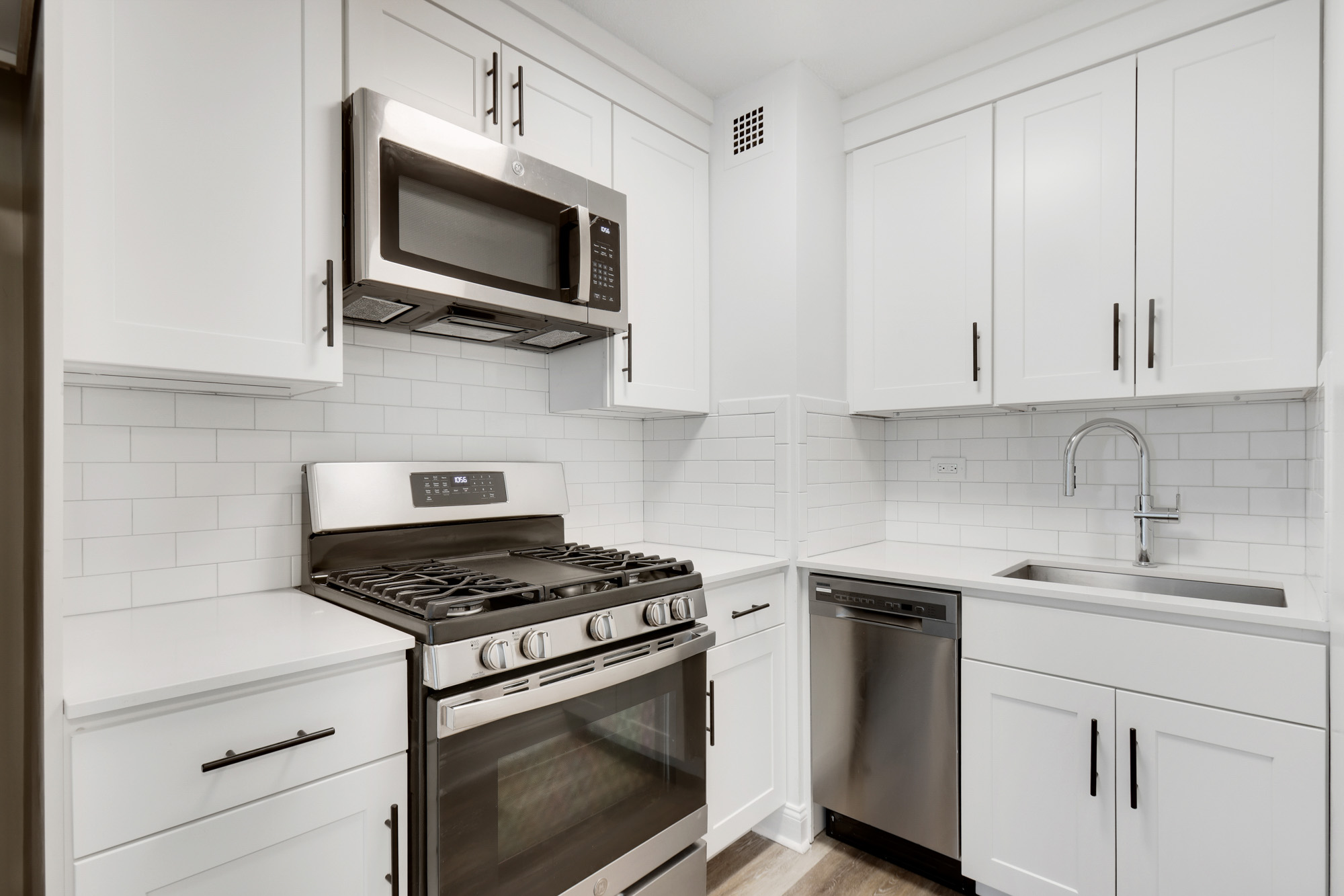 Corner kitchenette at Waterside Plaza with stainless steel appliances and deep farmhouse sink.