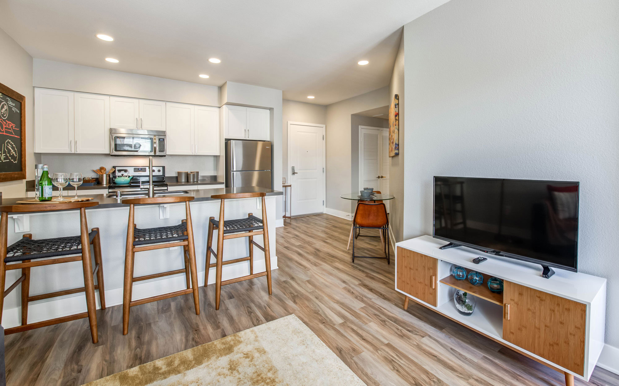 A modern kitchen with white cabinets, stainless steel appliances, and a kitchen island with seating space at Alders luxury apartments in Northridge CA