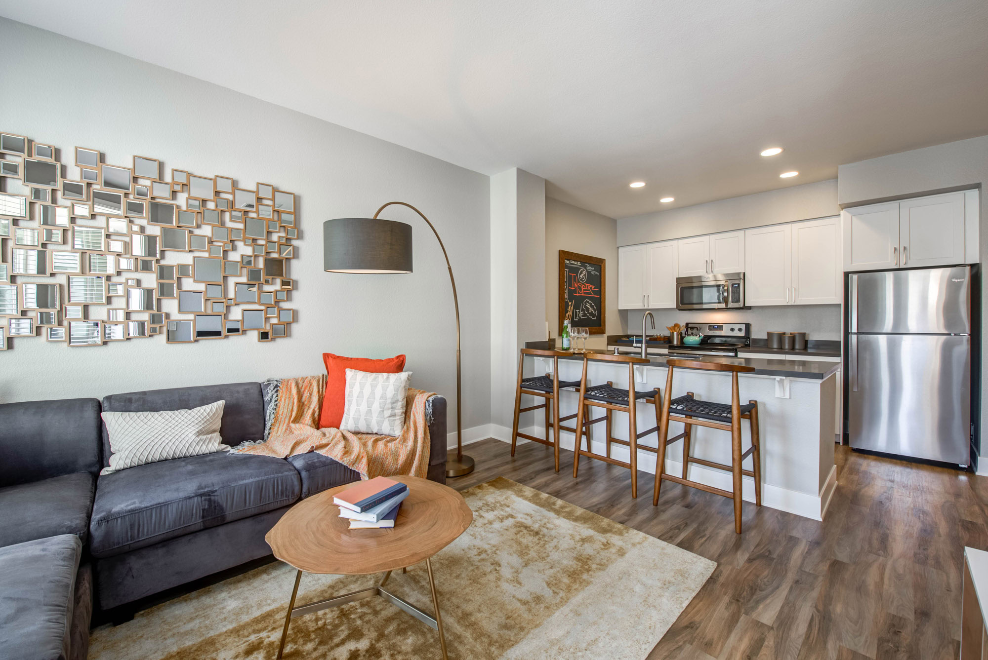 A modern living room with wood flooring leading into a kitchen at Alder apartments at Northridge California