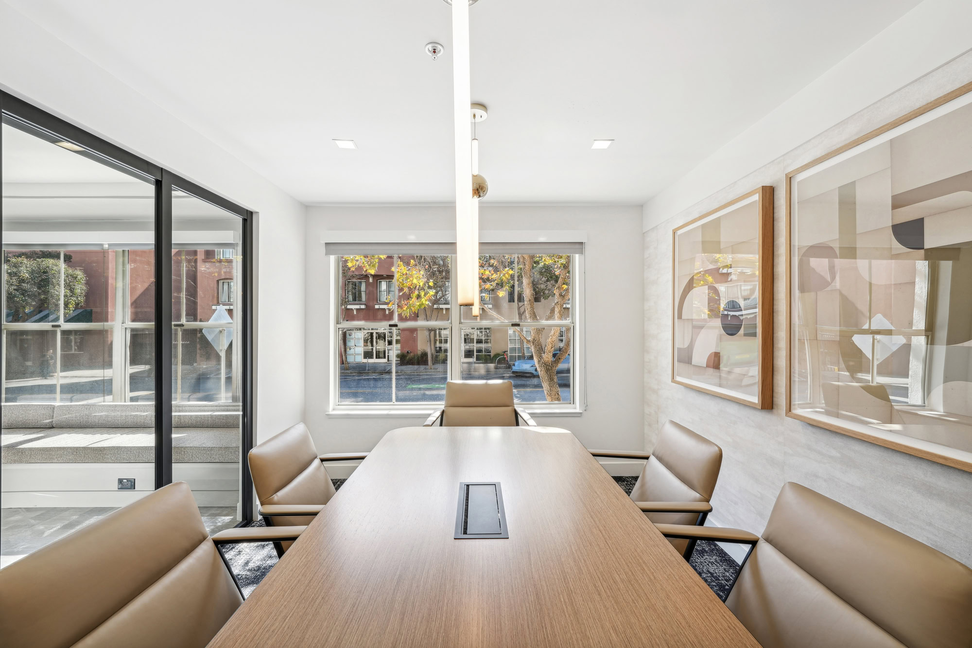 A conference table with tan leather chairs in a room with a large window and glass sliding doors at Bayside Village apartments in San Francisco