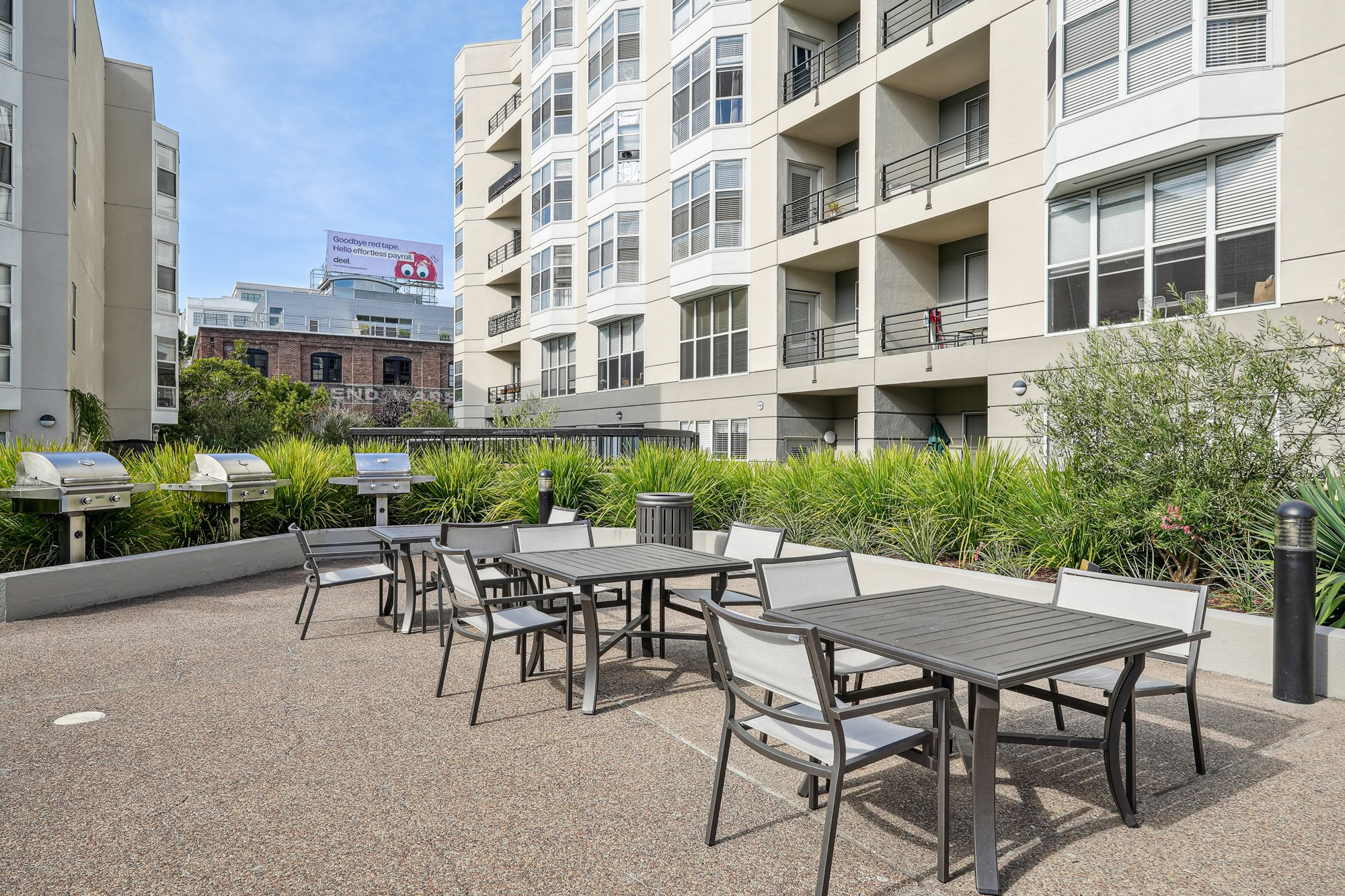 Three outdoor grills with with three dining tables at the courtyard of Bayside Village apartments in San Francisco