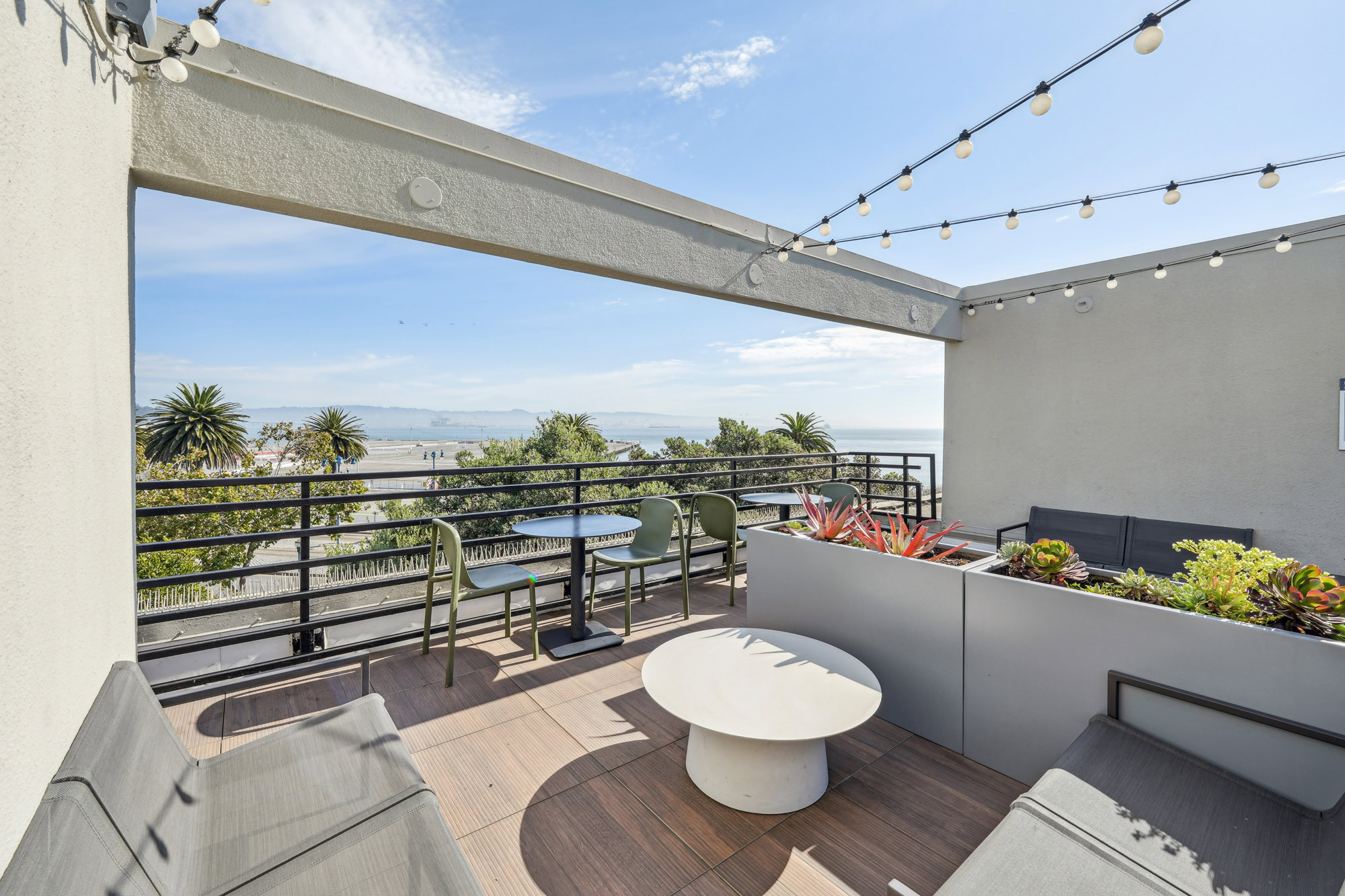A rooftop deck with lounging chairs and dining tables at Bayside apartments in San Francisco