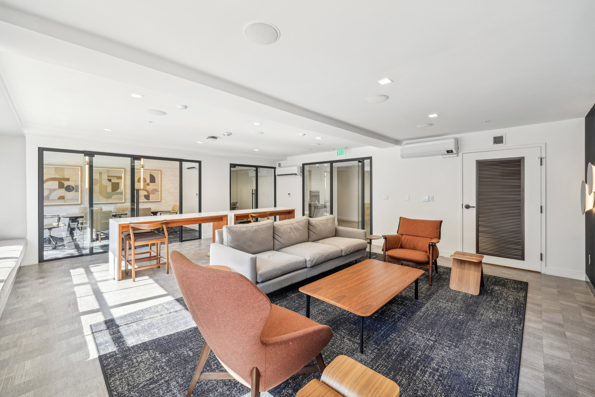 A lounge seating area, a long high table work space and conference room at Bayside apartments in San Francisco
