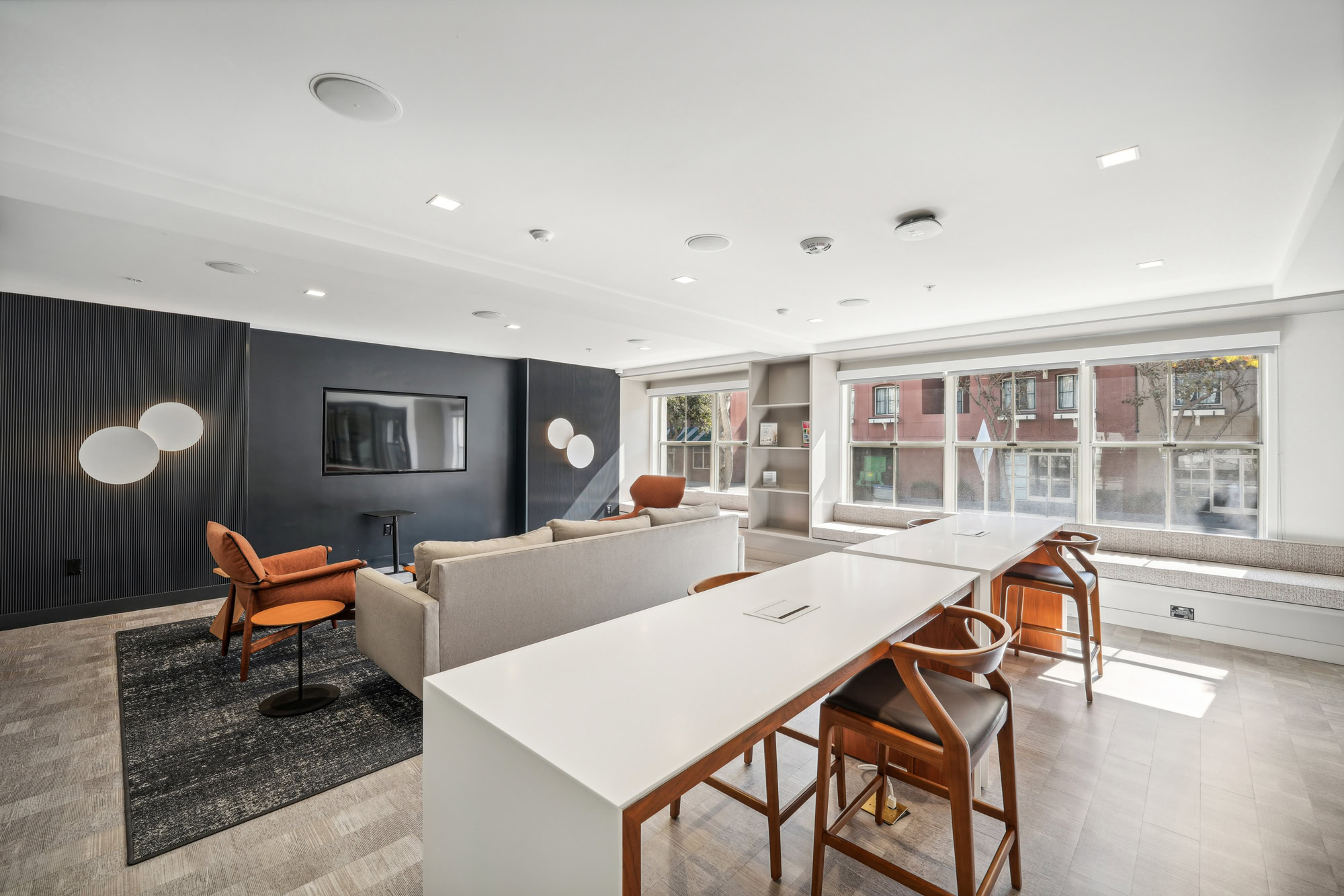 A modern lounge with two long work high tables behind a tv lounge at Bayside Village apartments in downtown San Francisco