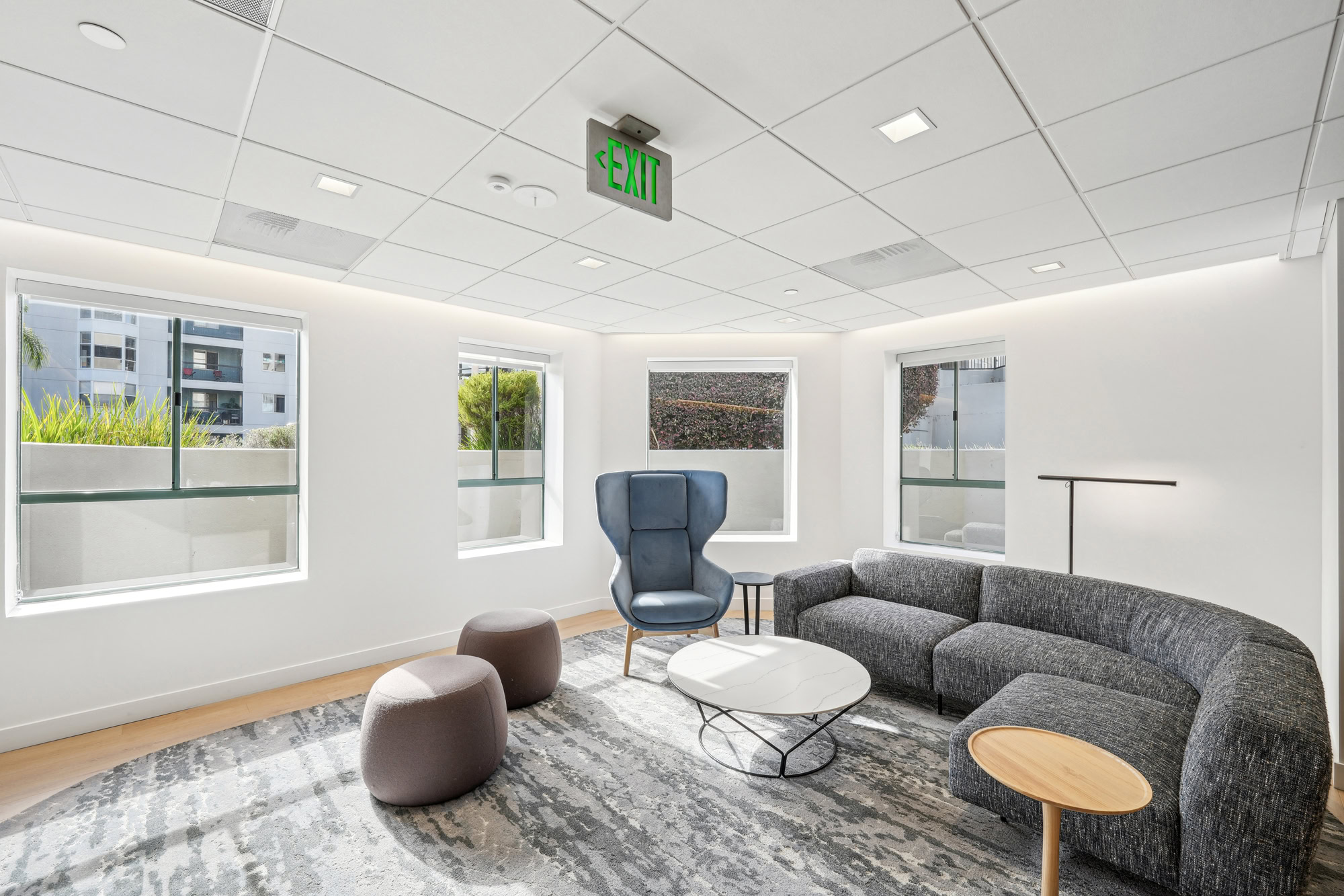 A modern lounge seating area with several windows at Bayside Village apartments in downtown San Francisco