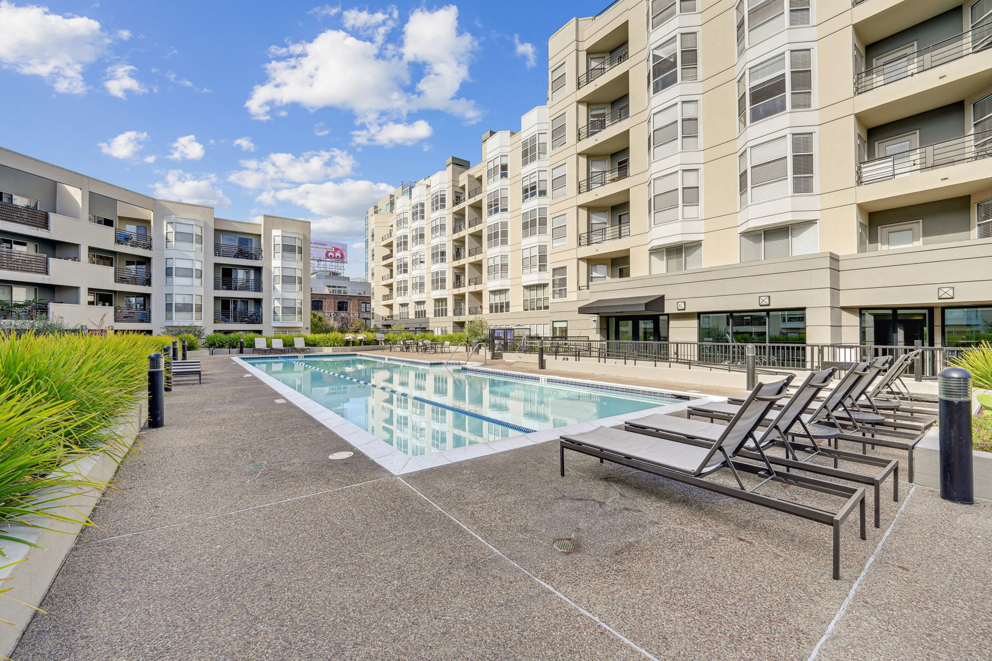 A long pool with two lanes and lounging chairs Bayside Village modern apartments surrounding it in downtown San Francisco