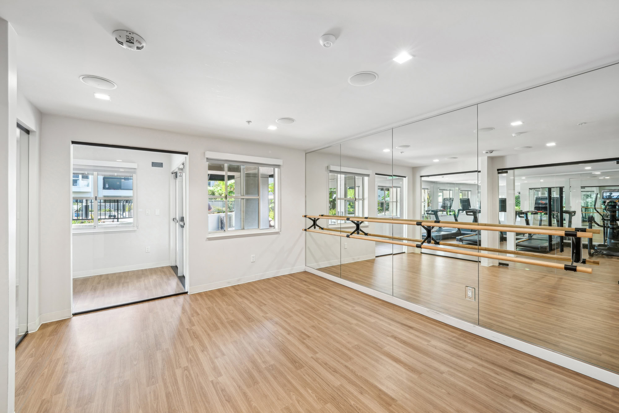 A yoga studio with a wall mirror, wood floors, and a window at Bayside Village modern apartments in San Francisco