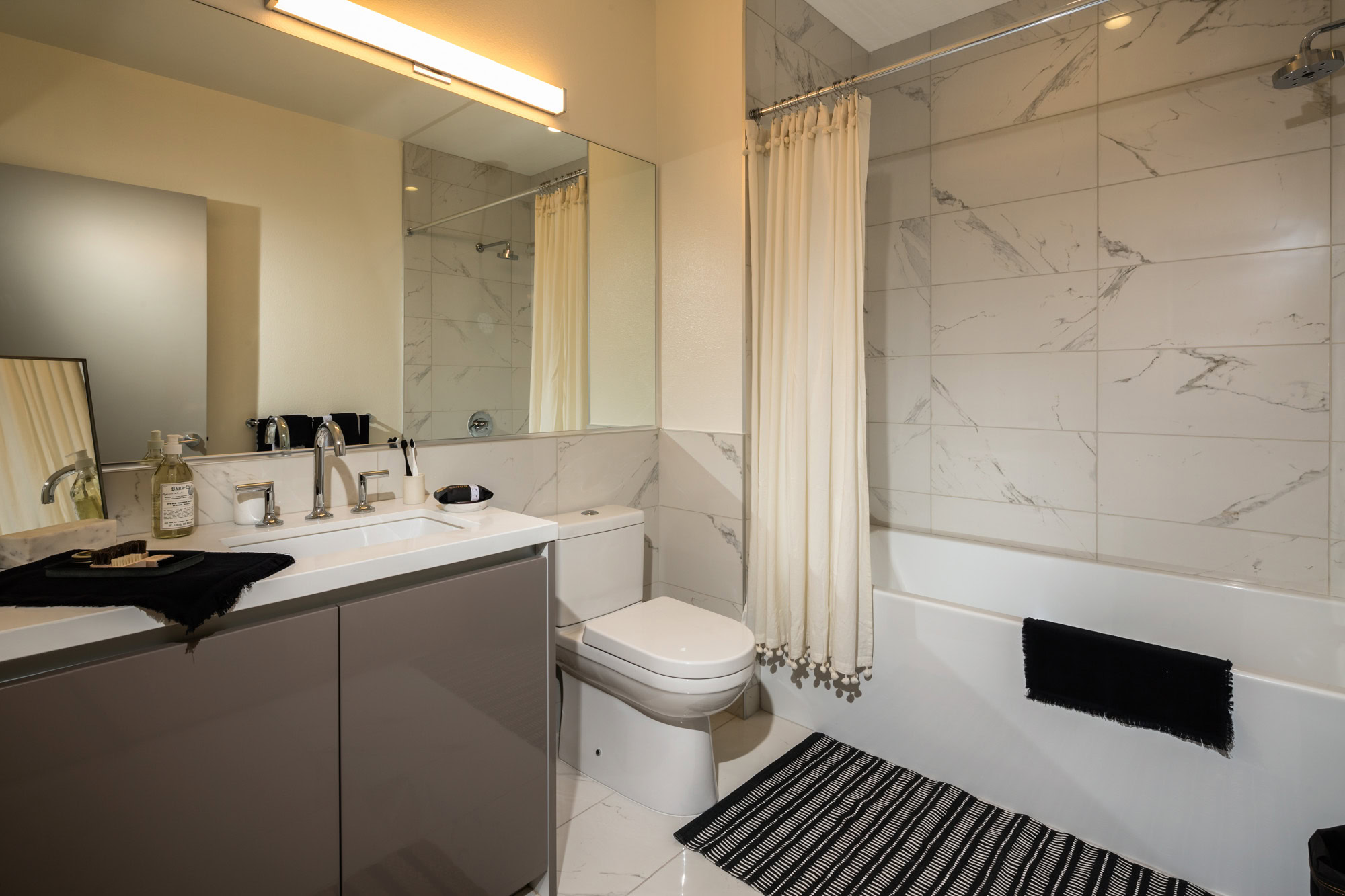 A modern, spa-like bathroom with a large mirror accross the wall at 8th and Grands luxury apartments in Los Angeles