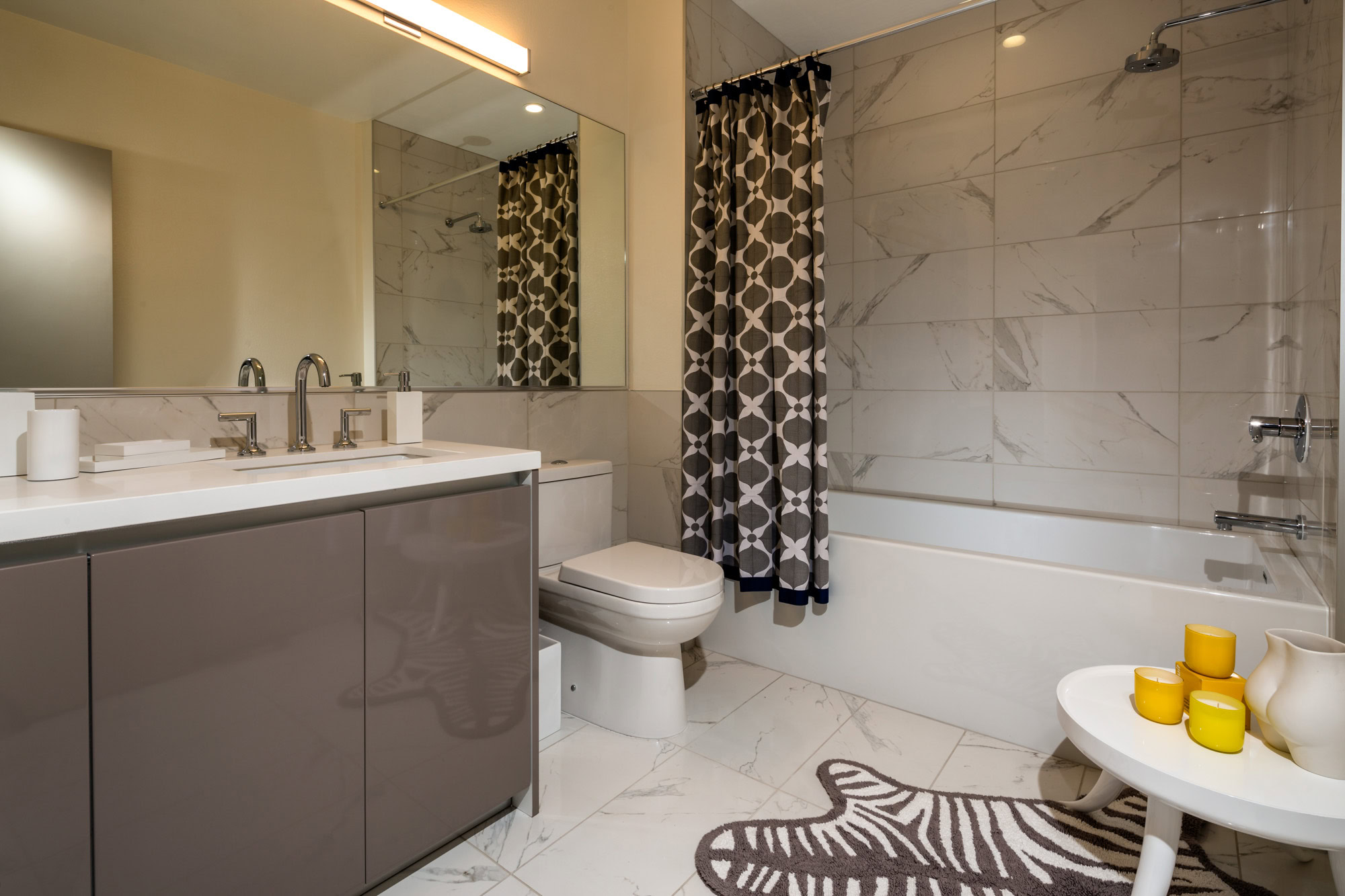 A modern, spacious bathroom with a mirror accross the wall and storage space below the sink in Downtown LA