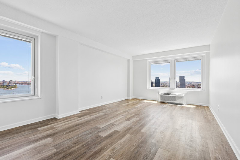 Newly renovated apartment with plank-style flooring, white frame windows with a city view.