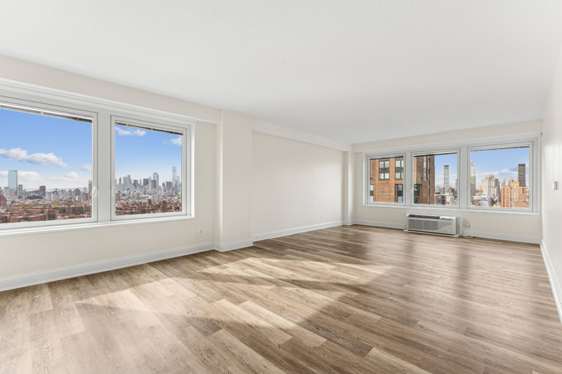 Newly renovated apartment with plank-style flooring, white frame windows on two walls offering great views and natural light.