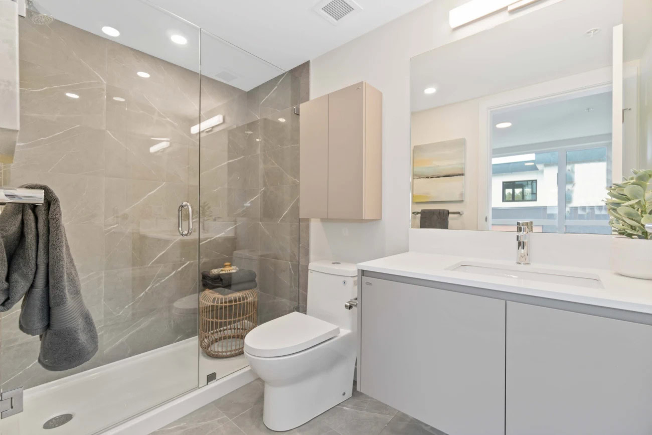 A spa-like bathroom with a large vanity sink counter and standing shower at the Hendry Place luxury apartments in Vancouver