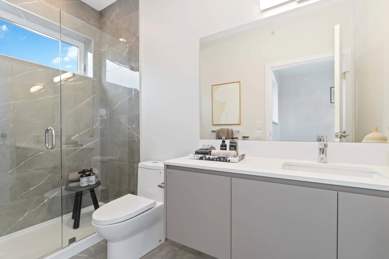 A spa-like bathroom with a large vanity sink counter and standing shower at the Hendry Place luxury apartments in Vancouver