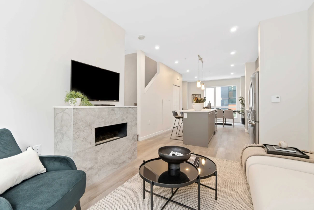 A open plan living room with a fireplace, leading to a kitchen island and dining area at Hendry Place luxury east Vancouver apartments for rent
