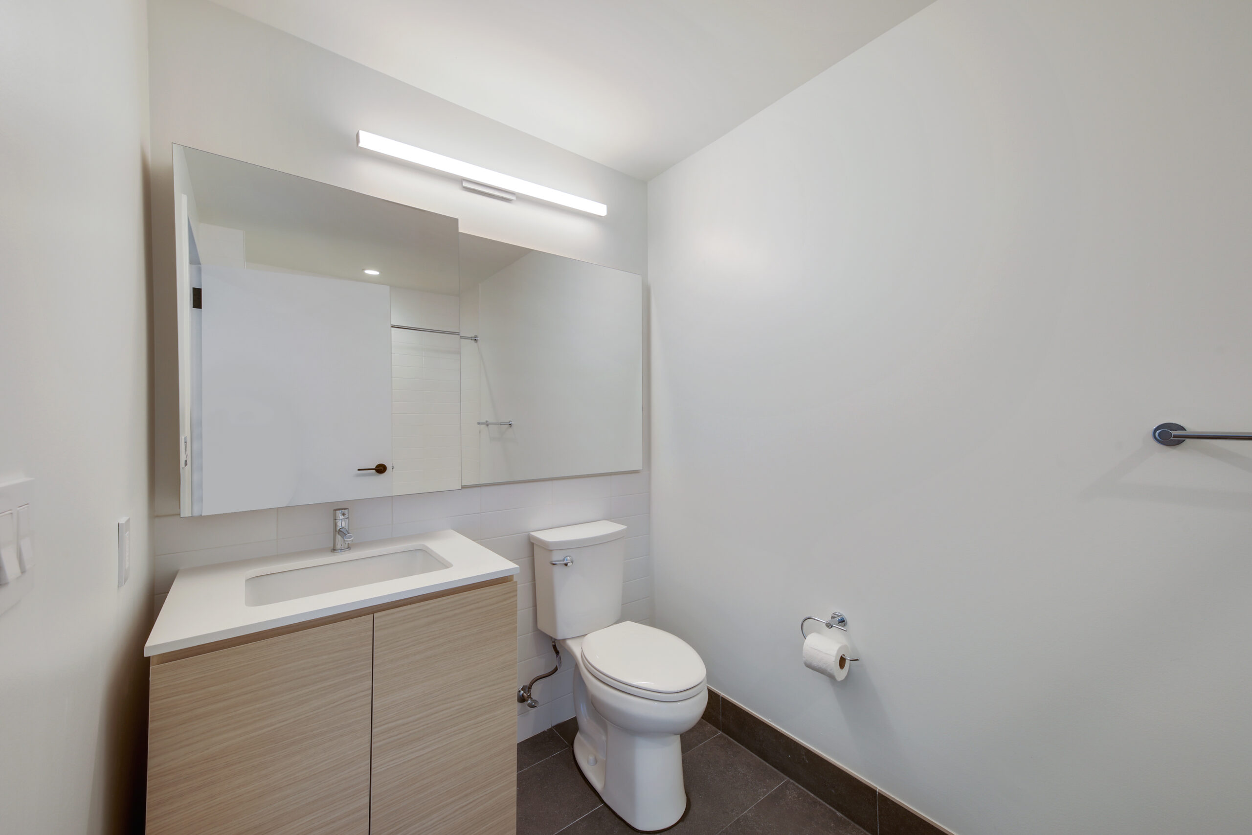 The bathroom with light natural cabinetry and countertops in an affordable housing apartment at Eagle+ West.