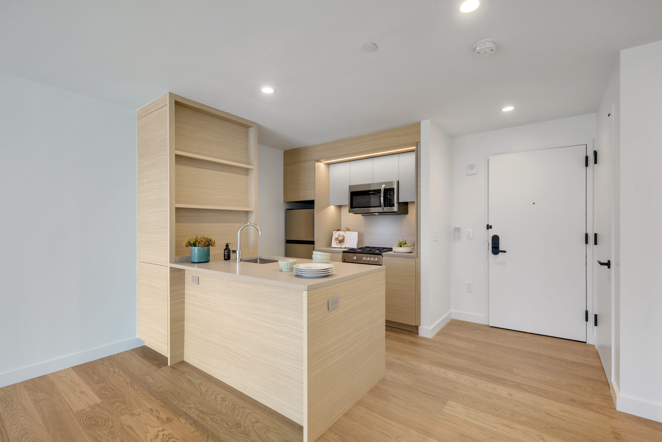 The kitchen with light natural cabinetry and countertops in an affordable housing apartment at Eagle+ West.