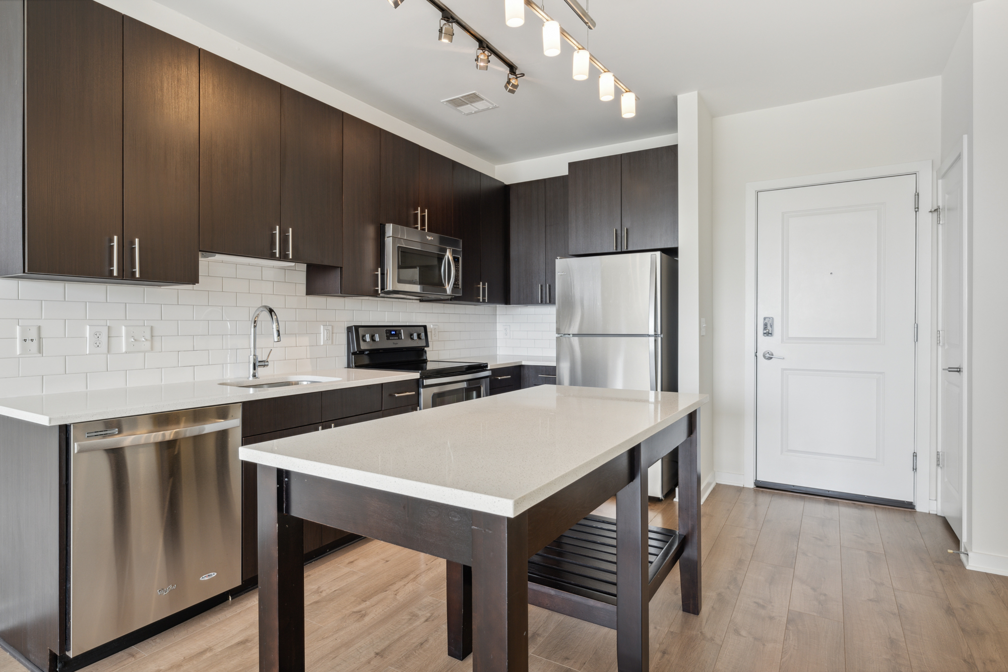 Dark kitchen cabinets and quartz countertops and a kitchen island.