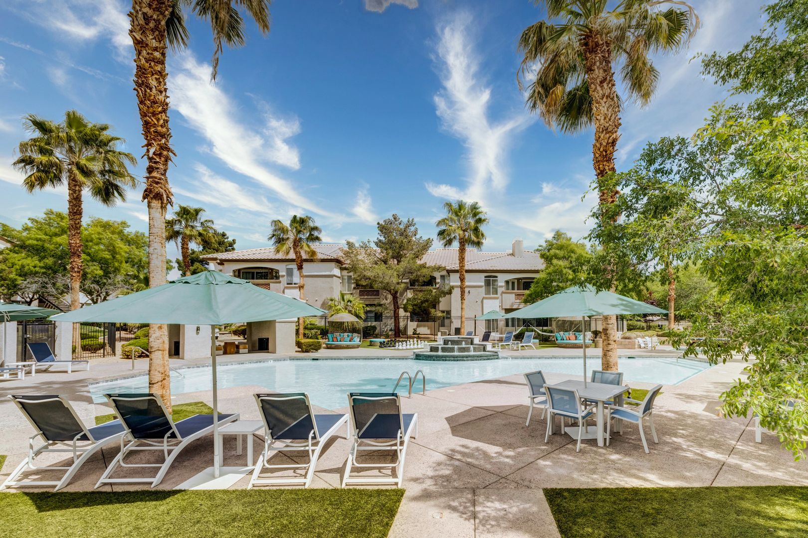 A pool with lounging chairs, umbrellas and cabana's at the Monaco Park Spring Valley apartments in Las Vegas
