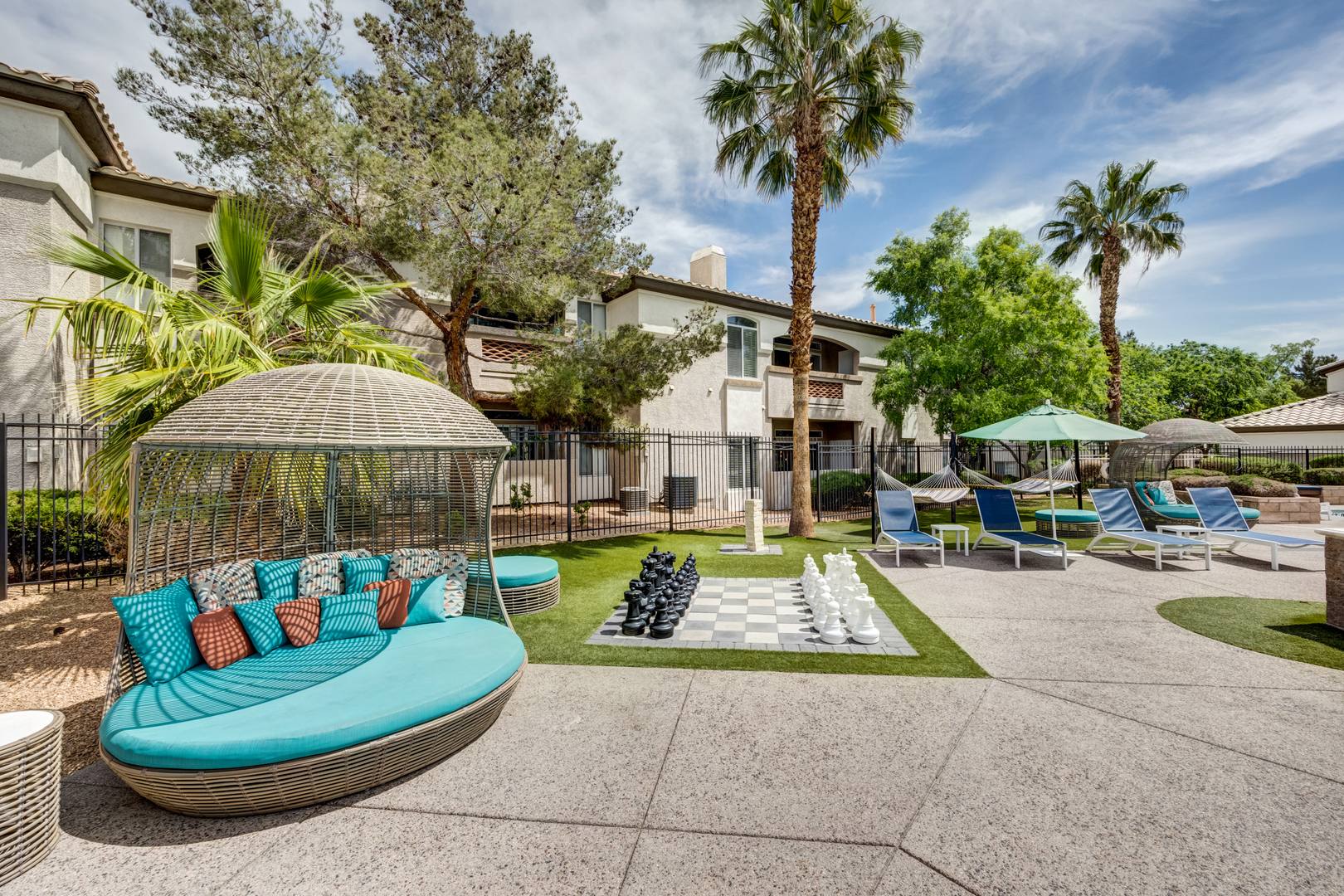 A pool side with a life lounging chairs, umbrellas and a life sized chess table at the Monaco Park Spring Valley apartments in Las Vegas