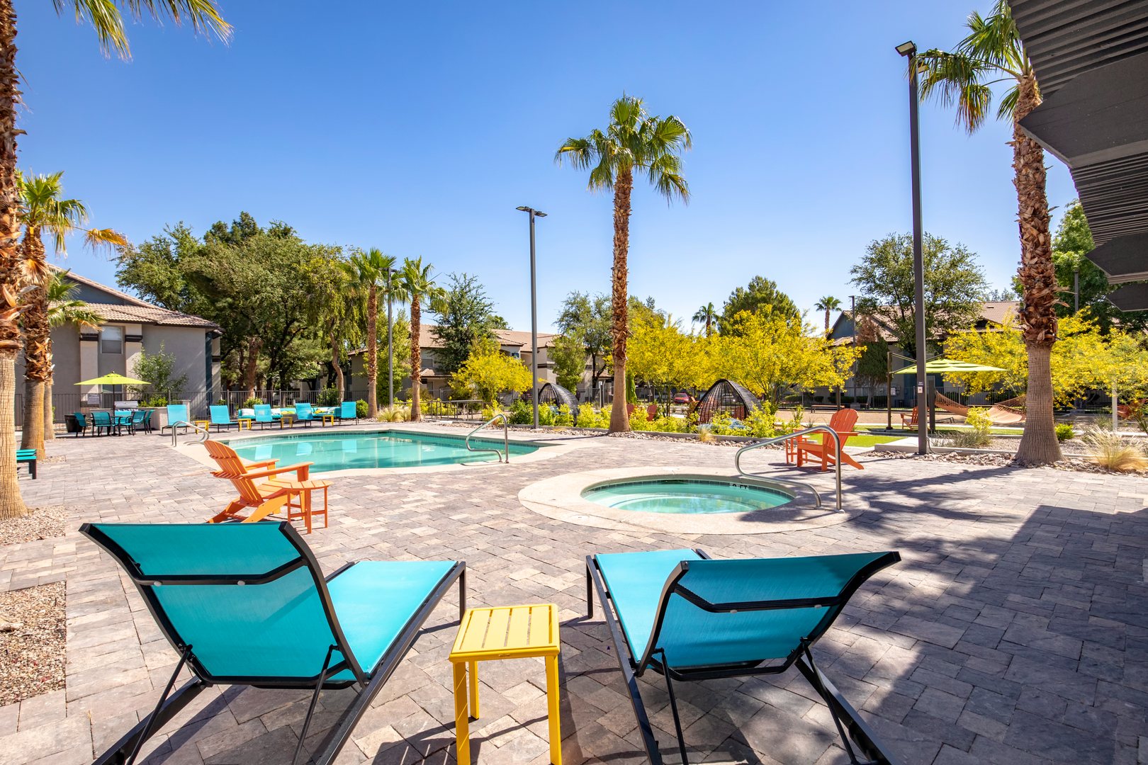 A pool and a jacuzzi surrounded by palm tree's and lounging chairs at Xander 3900 apartments in northwest Las Vegas