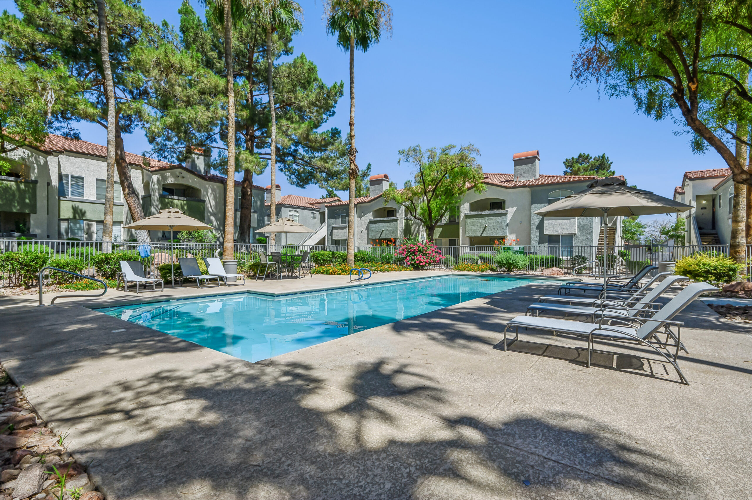 Second outdoor pool at Vintage Pointe with lounge chairs, umbrellas, landscaping, and surrounding apartment homes.