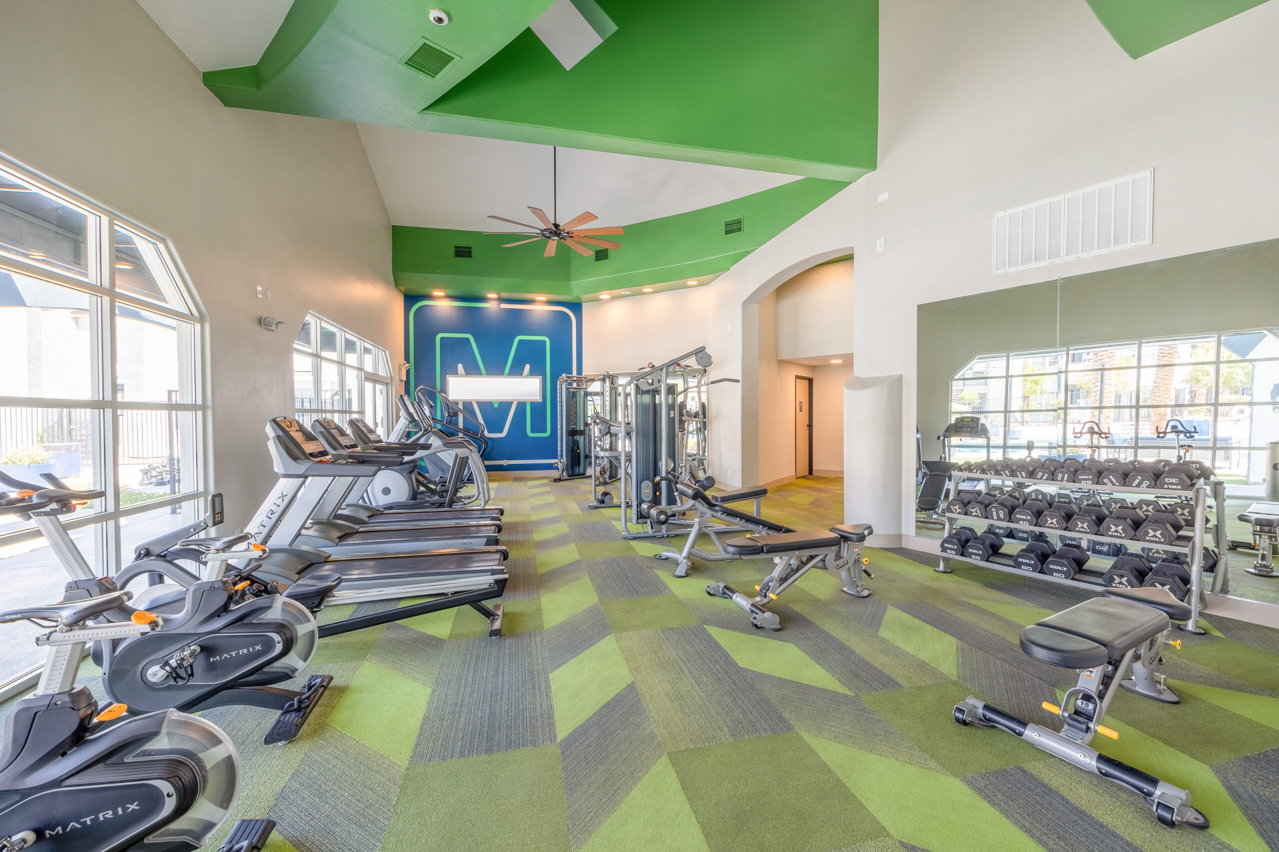 A vibrant fully equipped fitness center with elipticals, treadmills, cable machines, benches and weights at The Met apartments in Northwest Las Vegas