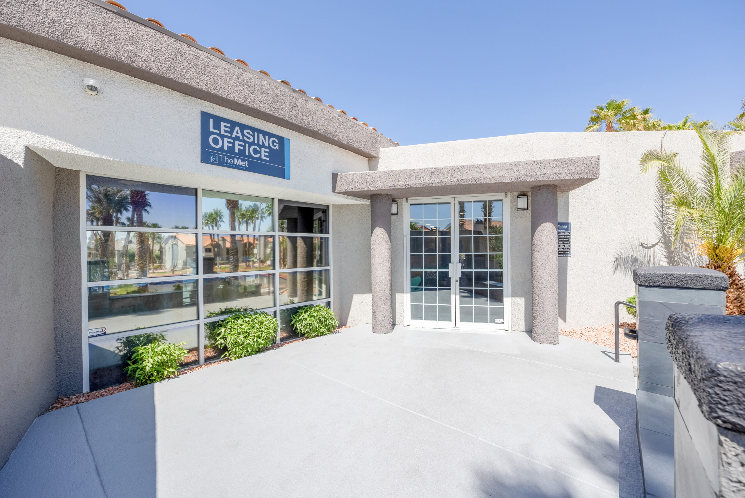 The leasing office building exterior with a blue sign on it at The Met, Northwest Las Vegas apartments for rent