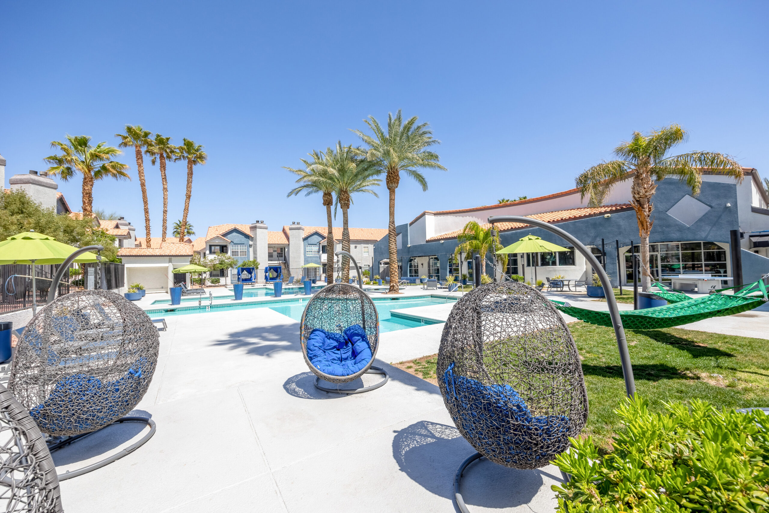 A resort-style pool area with blue hanging basket chairs at The Met Las Vegas apartments for rent