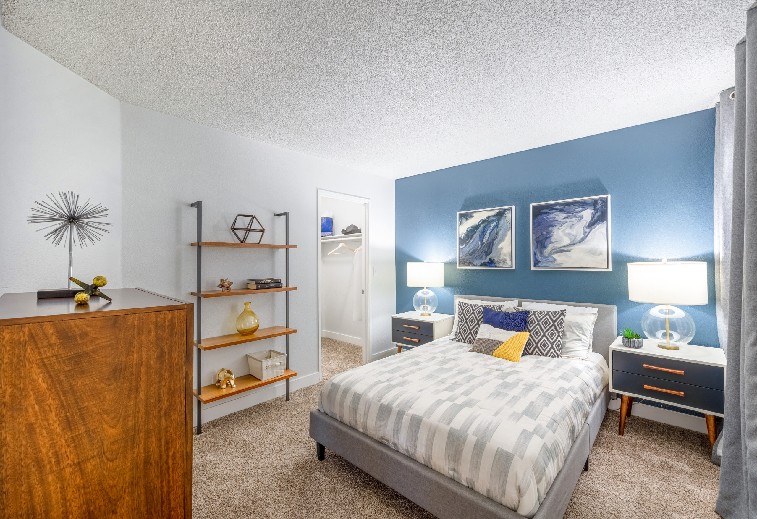 A carpeted bedroom with a walk-in closet and accent blue wall at The Met Las Vegas apartments for rent