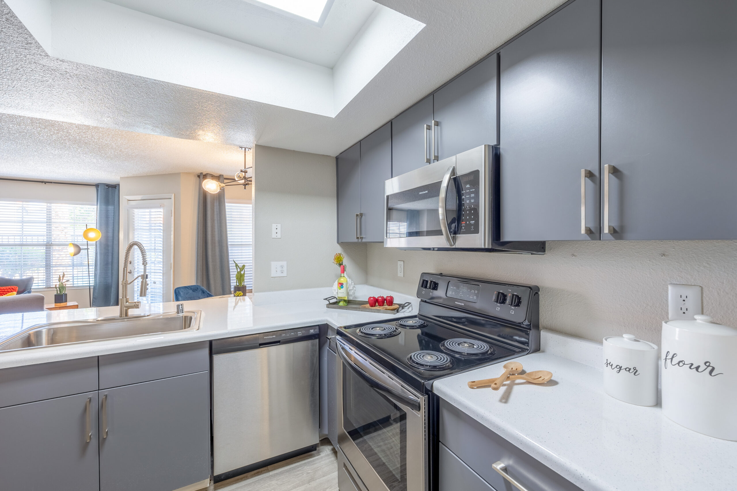 An L-shaped kitchen with stainless steel appliances, and white quartz counters at The Met Las Vegas apartments for rent