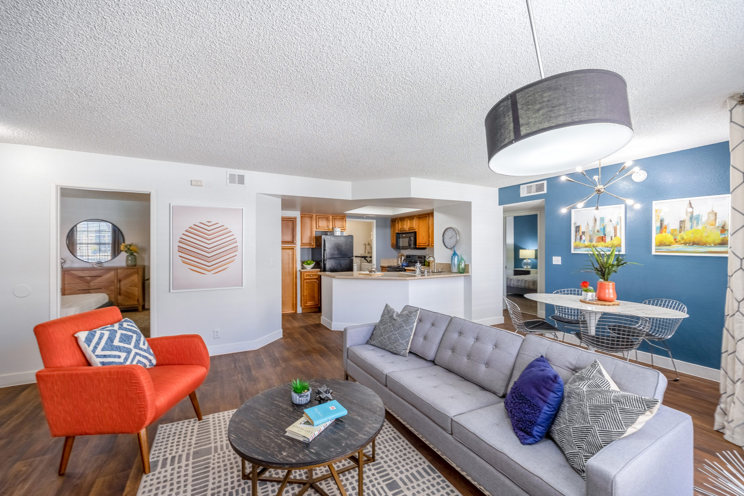 A living room with hardwood floors and a blue accent wall in an apartment at The Met Las Vegas
