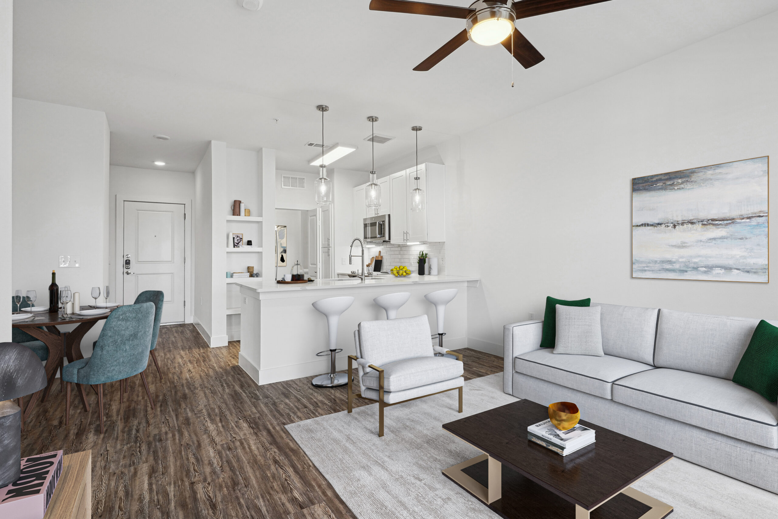 Living room with rug and matching couch, with a coffee table, dining room table, kitchen island with stools, and ceiling fans.