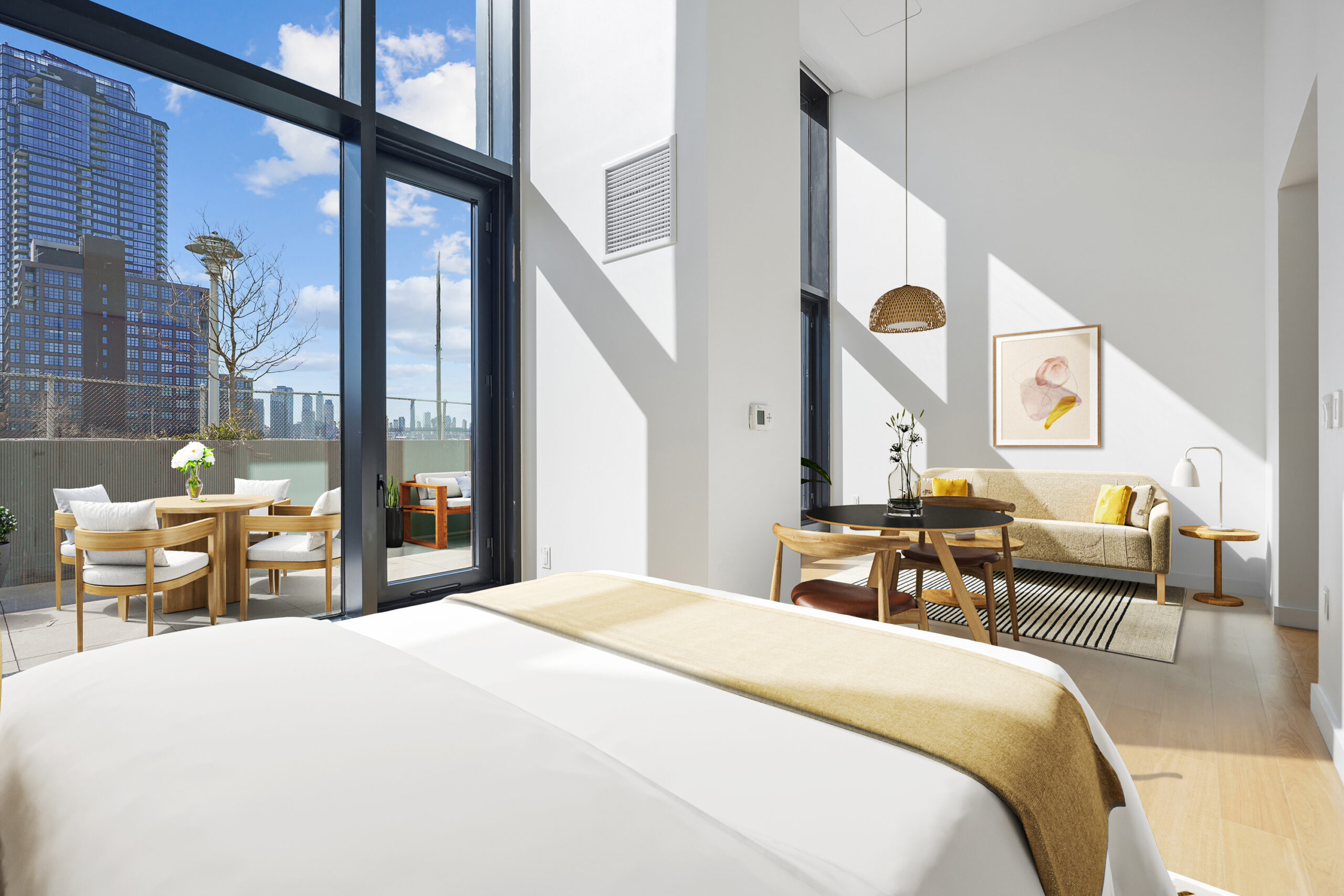 Studio apartment with bedroom, dining, and living areas and a view of the outdoor terrace with furniture.