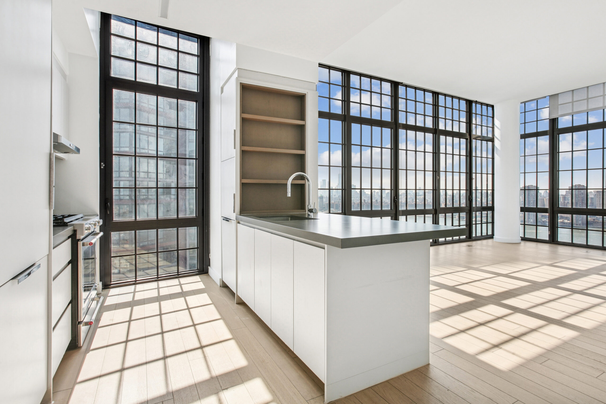 Spacious kitchen with island and built-in shelving and generous floor-to-ceiling windows offering water views