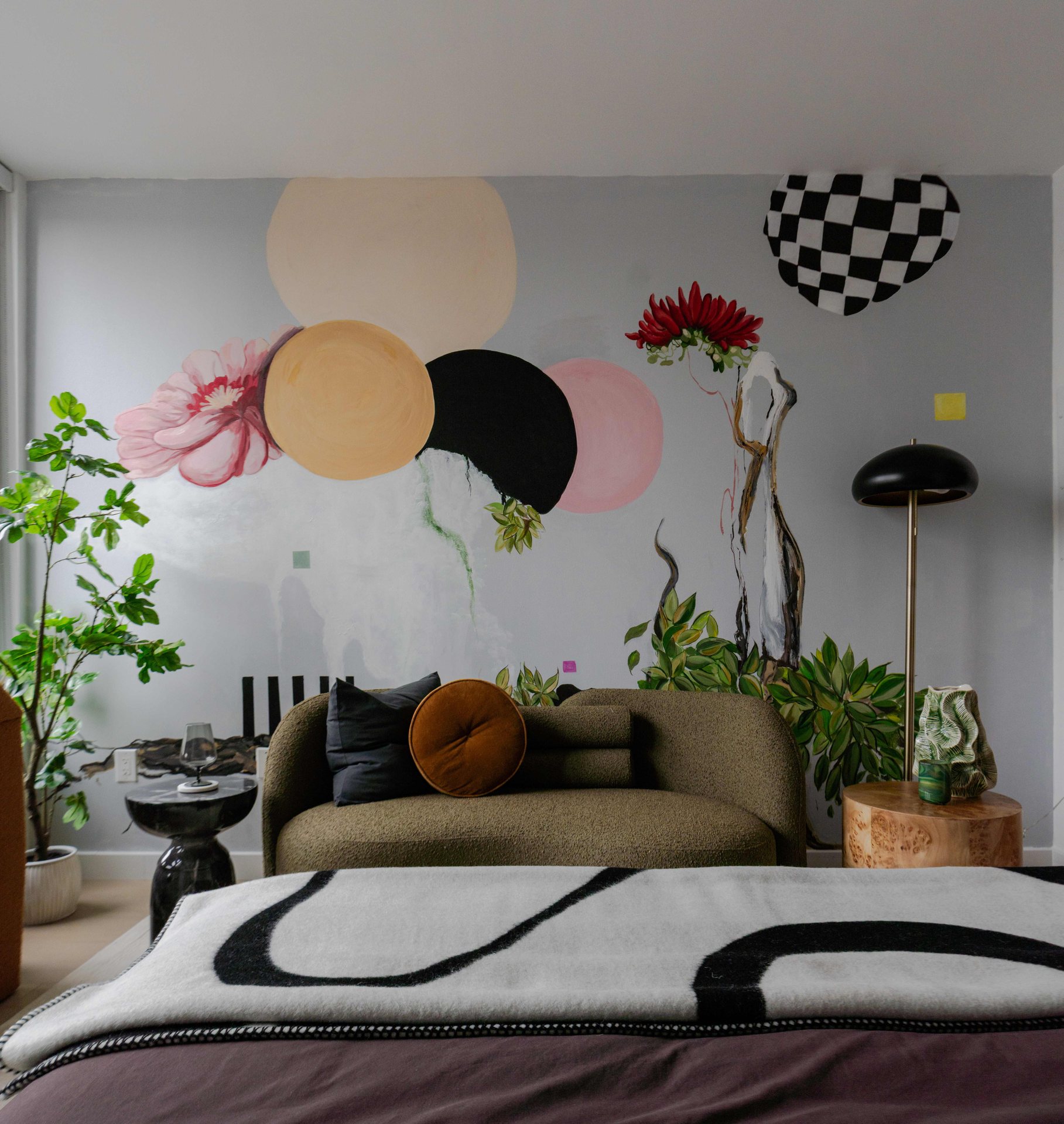 A bedroom with a large window and a colorful mural.