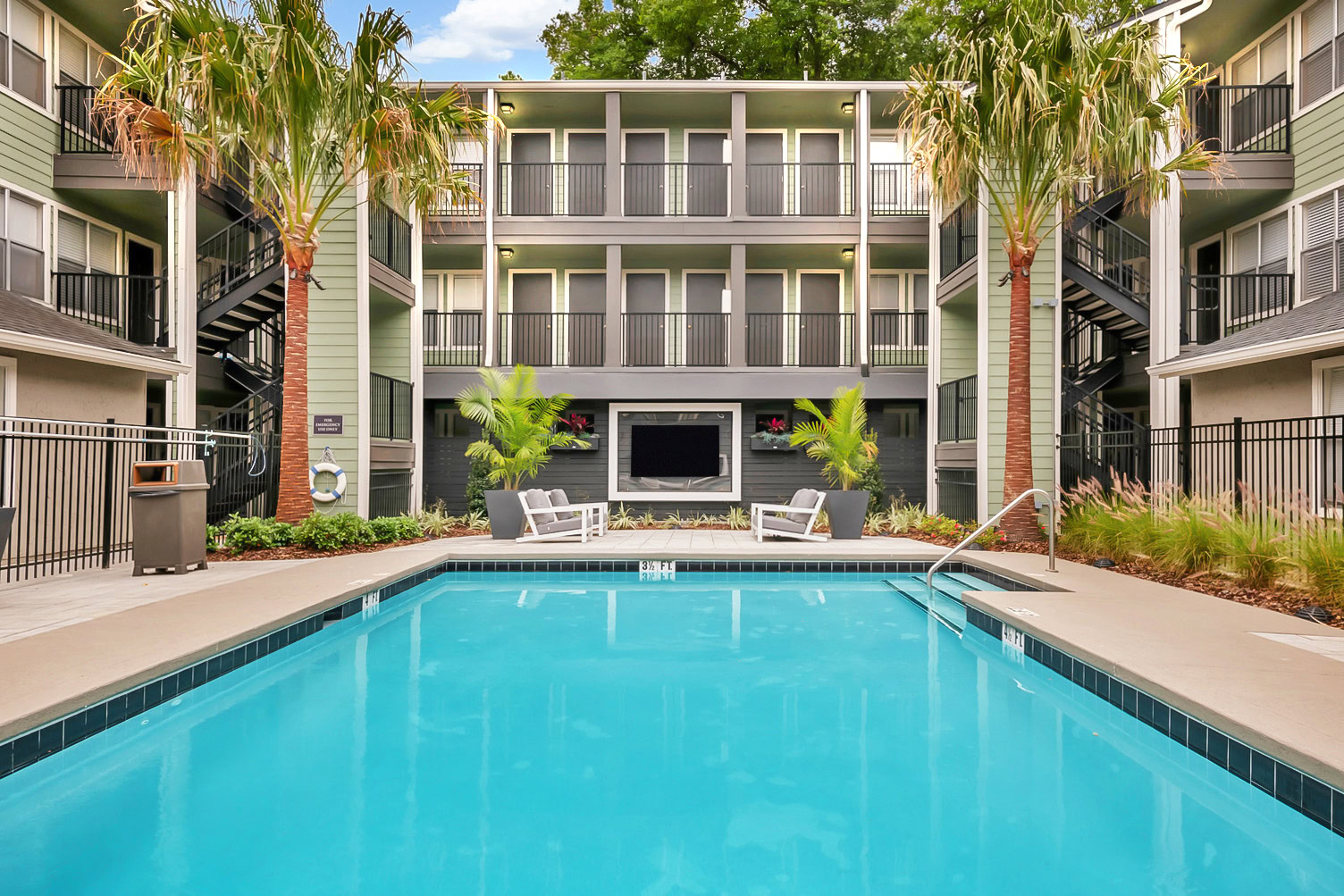 Courtyard swimming pool surrounded by palm trees and apartment buildings at Brookwood Club in Jacksonville.