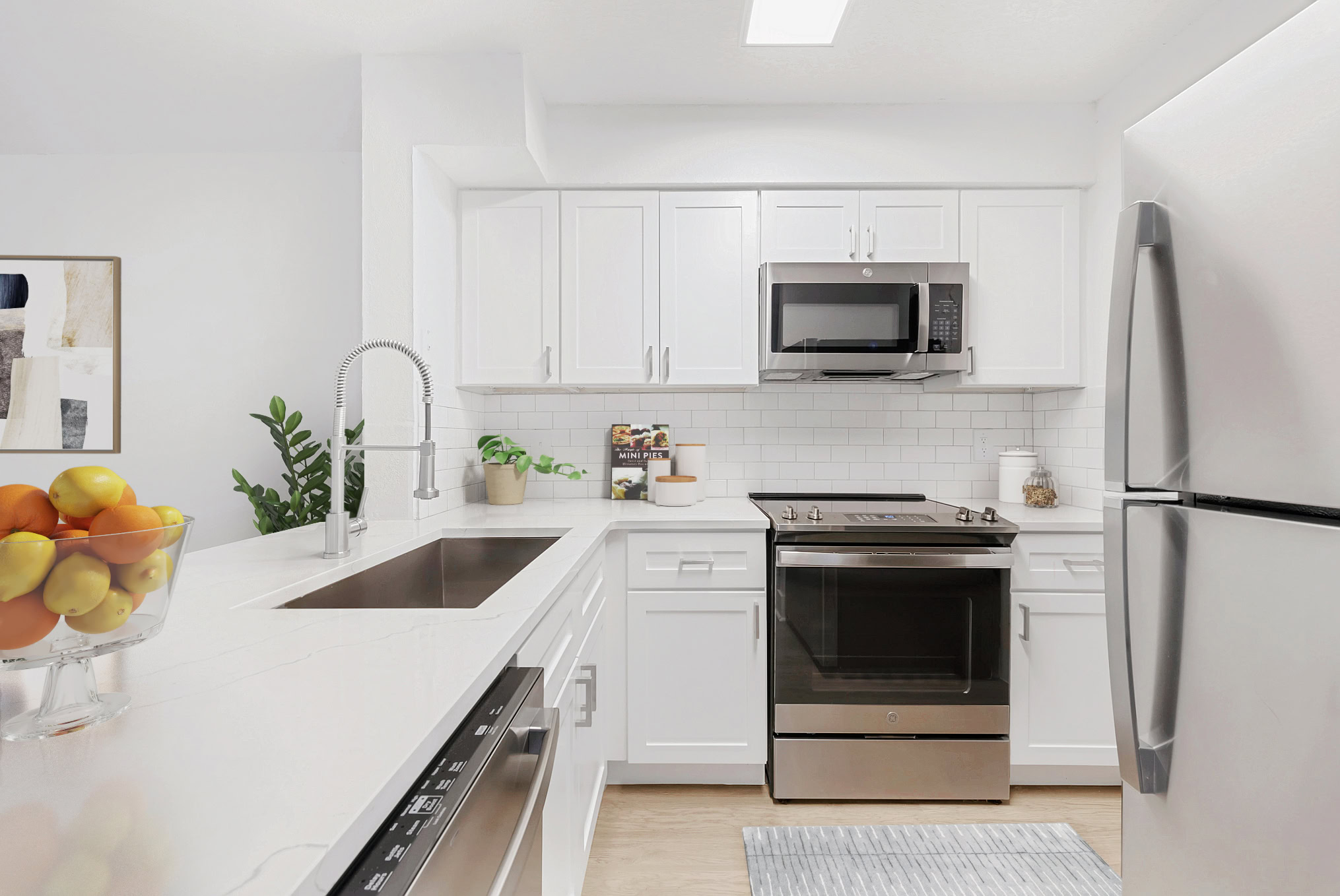 Modern apartment kitchen with white cabinetry, stainless steel appliances, subway tile
backsplash, and quartz-style countertops at Brookwood Club.