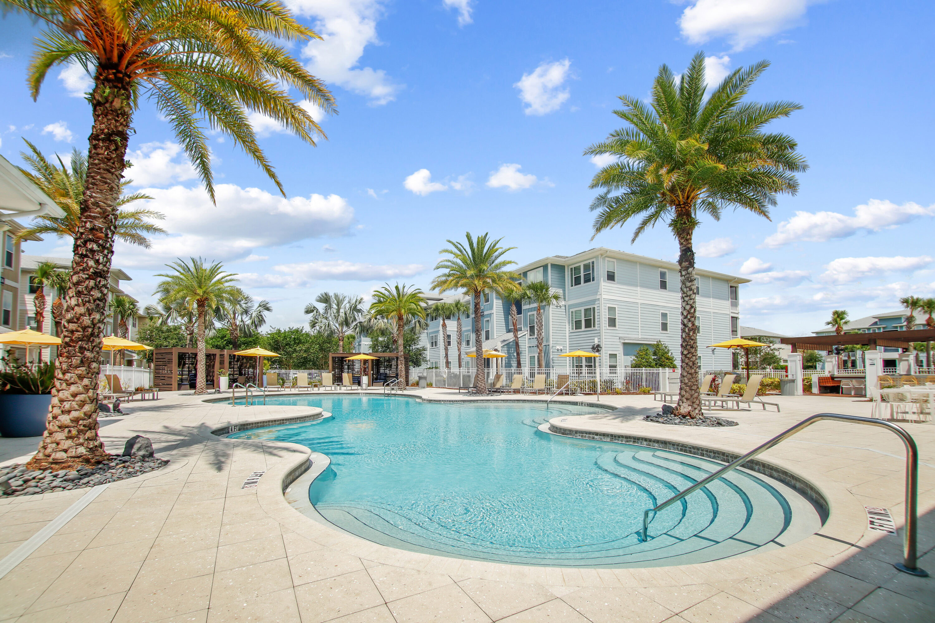 Resort-style swimming pool with palm trees and sun shelf at The Domain apartments near Orlando.