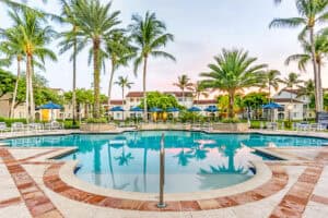 Resort-style swimming pool with palm trees and sun shelf at Miramar Lakes apartments in Miramar, Florida.