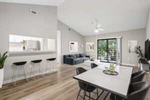 Open-concept apartment living and dining area with breakfast bar, vaulted ceiling, and wood-style flooring at South Pointe.