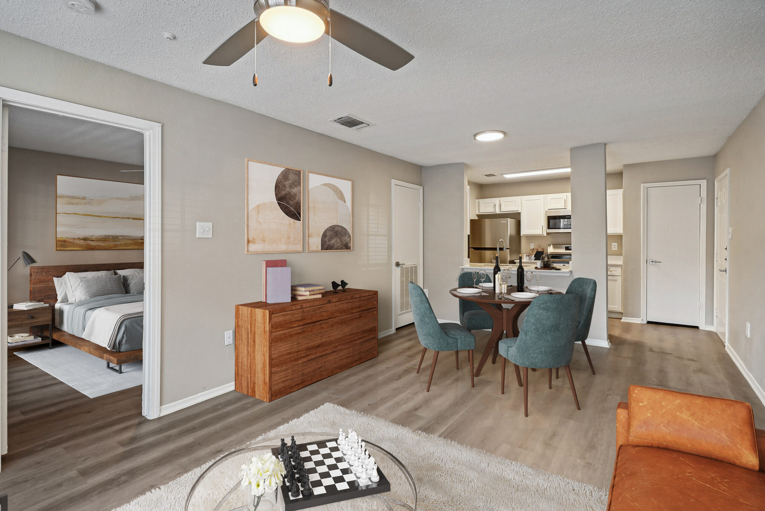 Open-concept living and dining area in an apartments in Garland Texas featuring wood-style floors, modern furniture, and a view into the kitchen and bedroom.